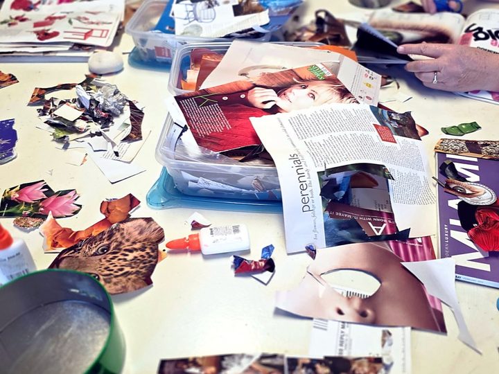 A collage-making workshop table covered in cut paper, magazines, and glue.