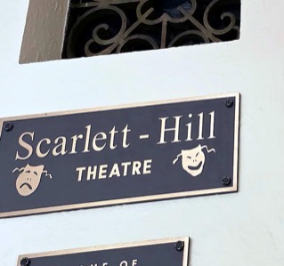 A brass theater sign reading Scarlett-Hill Theatre, mounted on a wall.